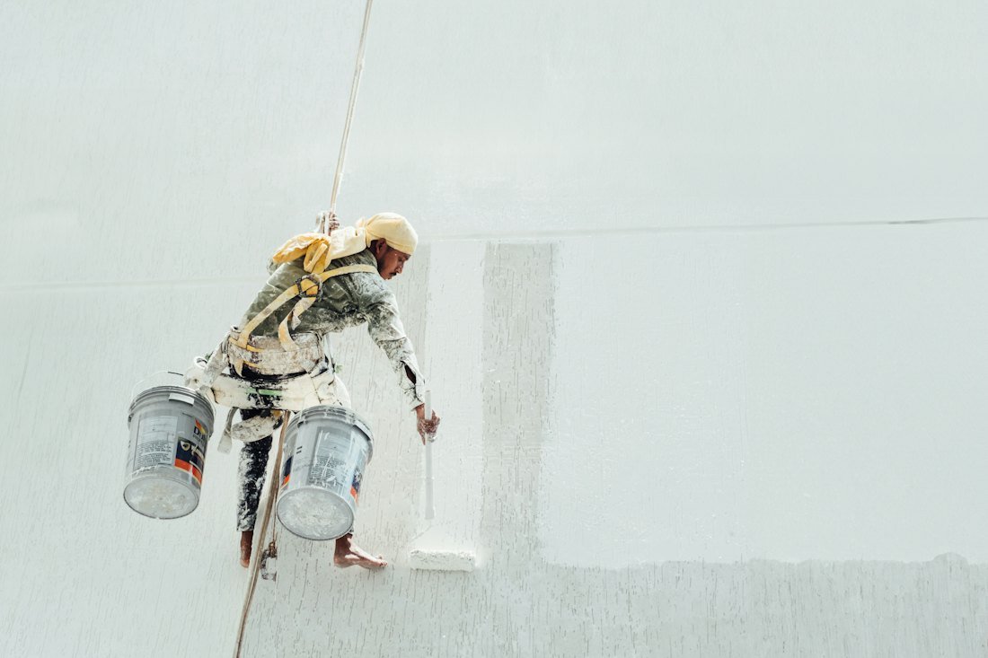 Pintor trabajando en una fachada blanca