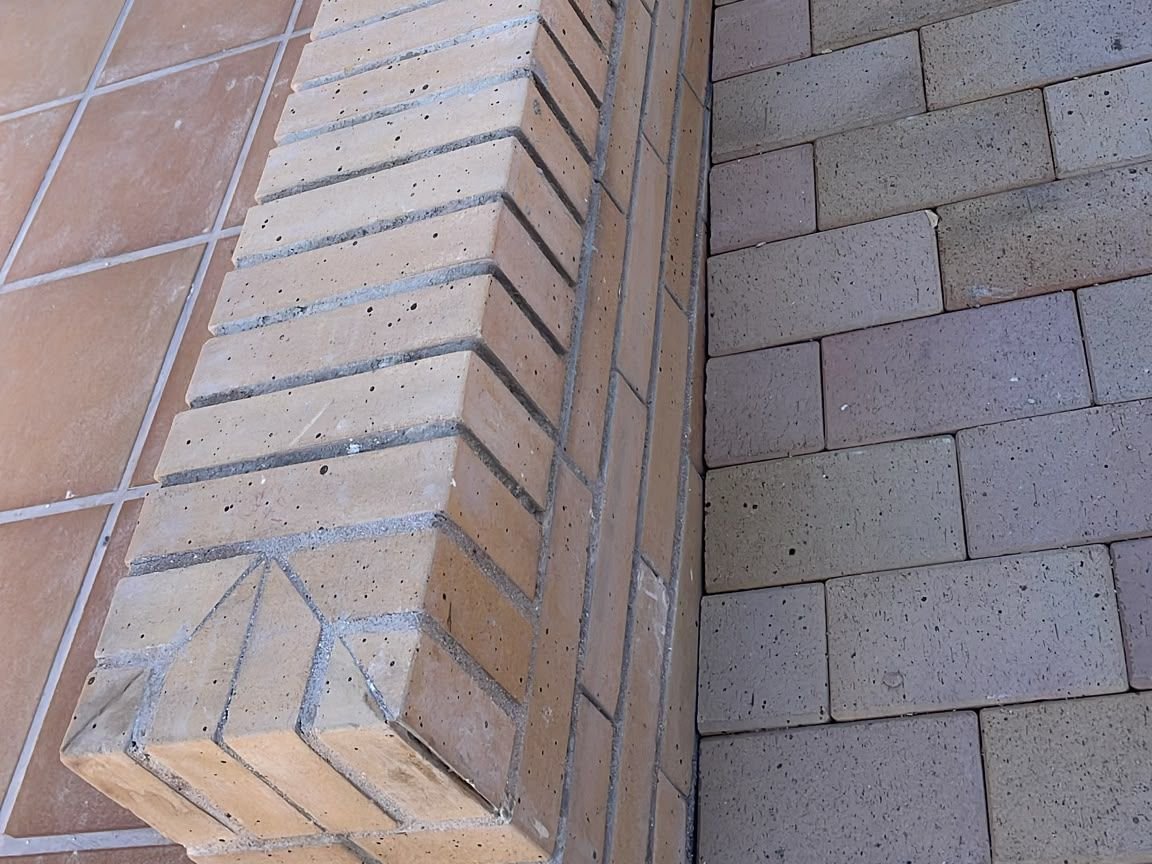 Detalle del murete de caravista rematado en sardinel junto al adoquín