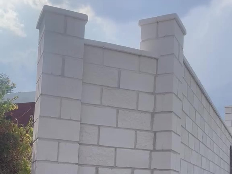 Muro de bloque split blanco con pilastras rematadas con albardilla